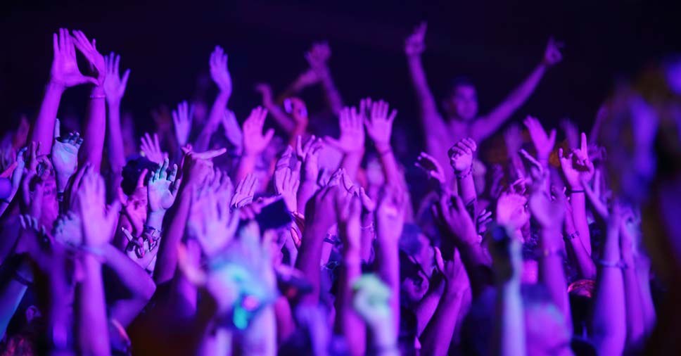 mãos levantada para o alto indicam uma multidão em um evento