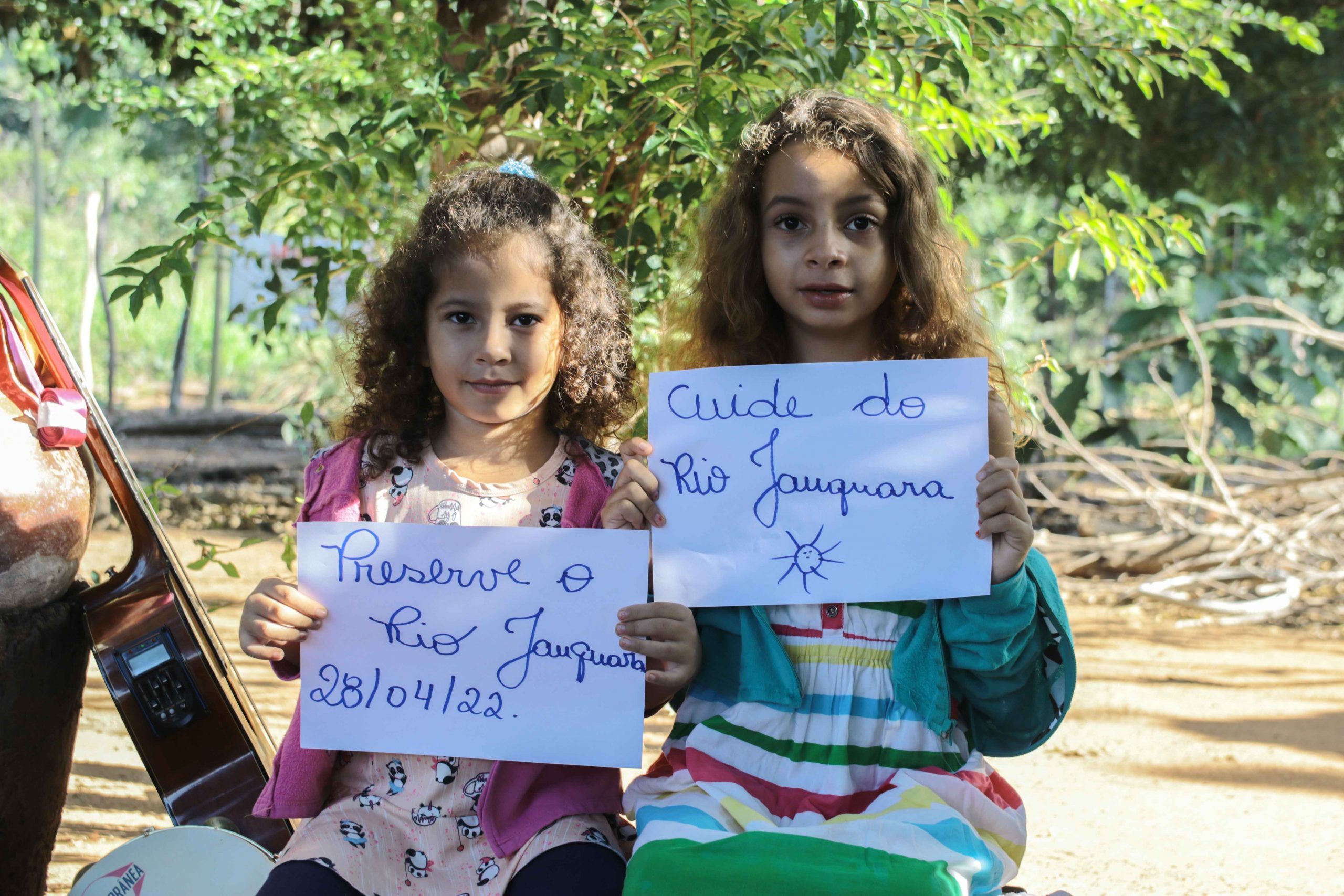 Duas crianças seguram folhas de protesto pela defesa do rio Jauquara