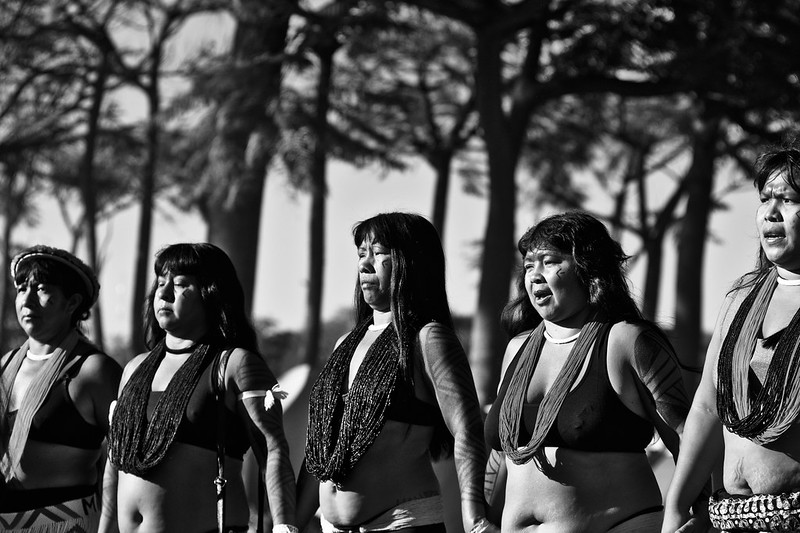 Mulheres indígenas seguram as mãos em linha - foto em preto e branco