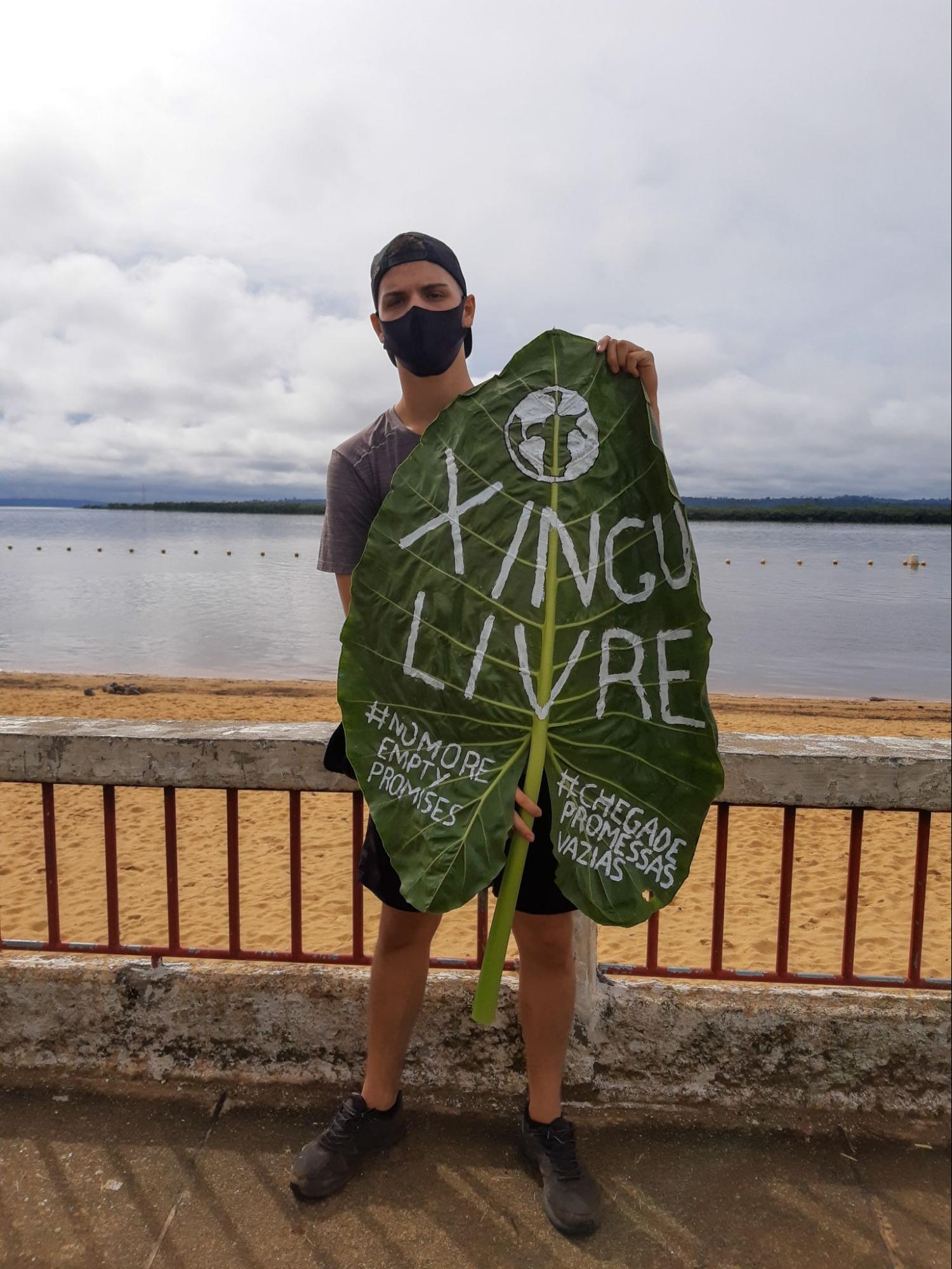 jovem ativista, segura um cartaz feito de folha de taioba com a mensagem "xingu livre". Jovens pelo Futuro Xingu 