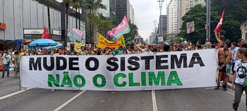 Protesto na paulista, ativistas pelo clima erguem faixa escrito "mude o sistema não o clima" como ação direta criativa