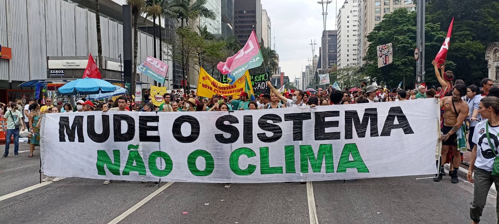 Protesto na paulista, ativistas pelo clima erguem faixa escrito "mude o sistema não o clima" como ação direta criativa