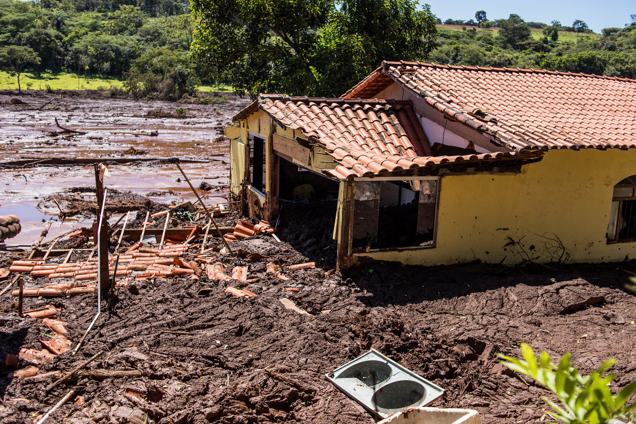 Casa amarela destruiída em meio à lama e entulhos