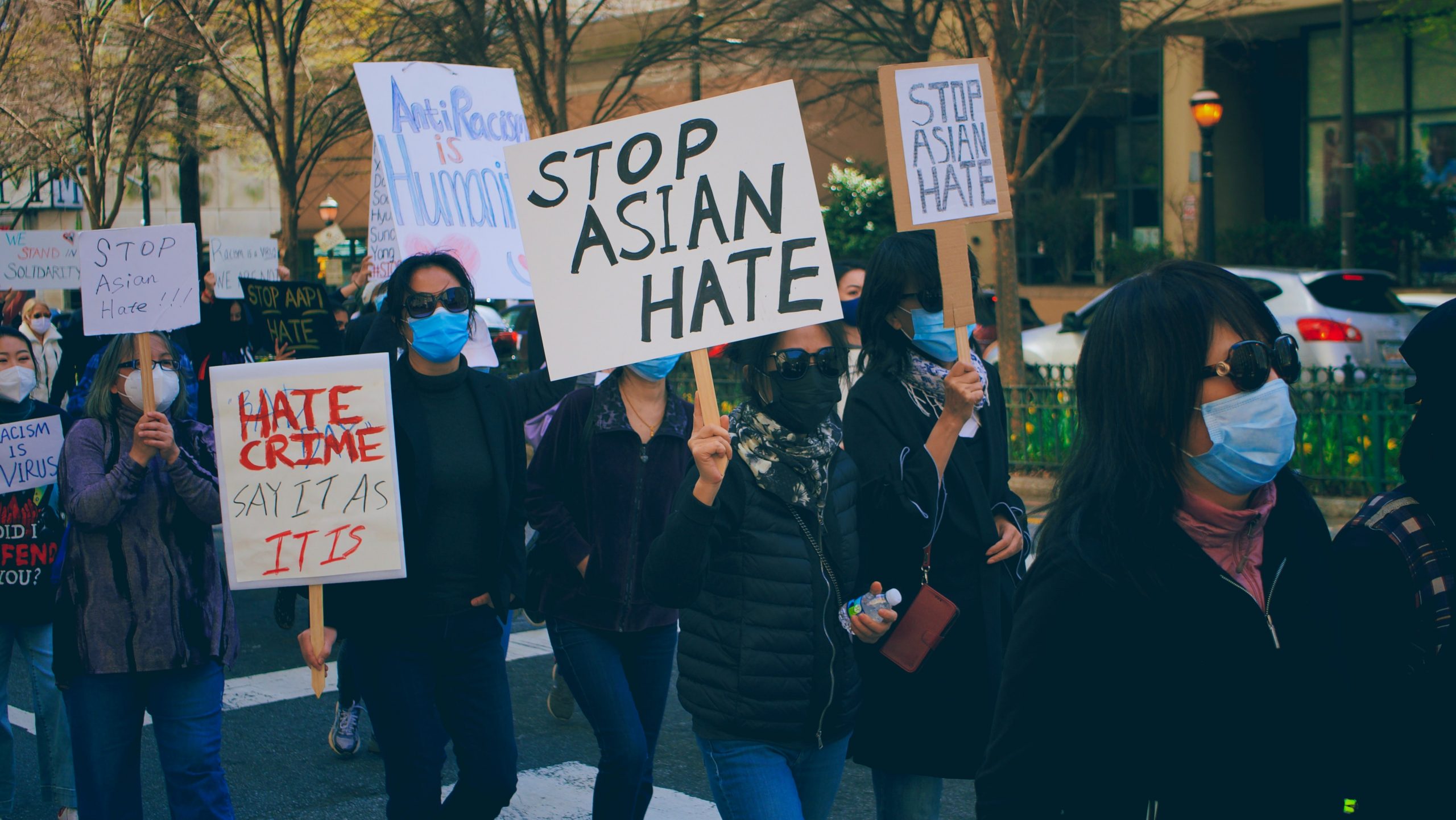 Grupo de pessoas asiáticas protestam na rua segurando placas com dizeres como "stop asian hate [parem de odiar asiáticos]