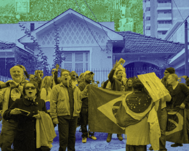 Pessoas protestam em frente a uma casa, segurando bandeiras do Brasil